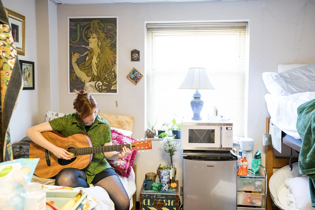 Student playing a guitar in their dorm room. 